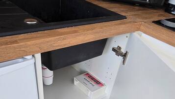 A kitchen with a wooden countertop, a black microwave, and a patterned tile floor.