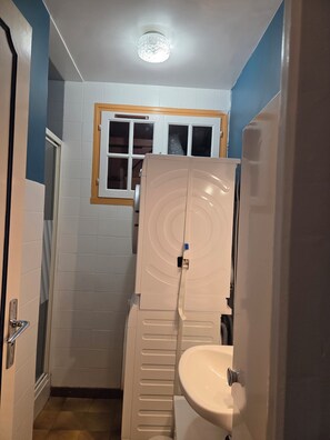 Ein kleines Badezimmer mit Toilette, Waschbecken und einem Fenster über dem Spiegel.