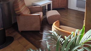 Ein gemütliches Wohnzimmer mit Holzboden, einer Couch, einem Fernseher und einem kleinen Tisch.