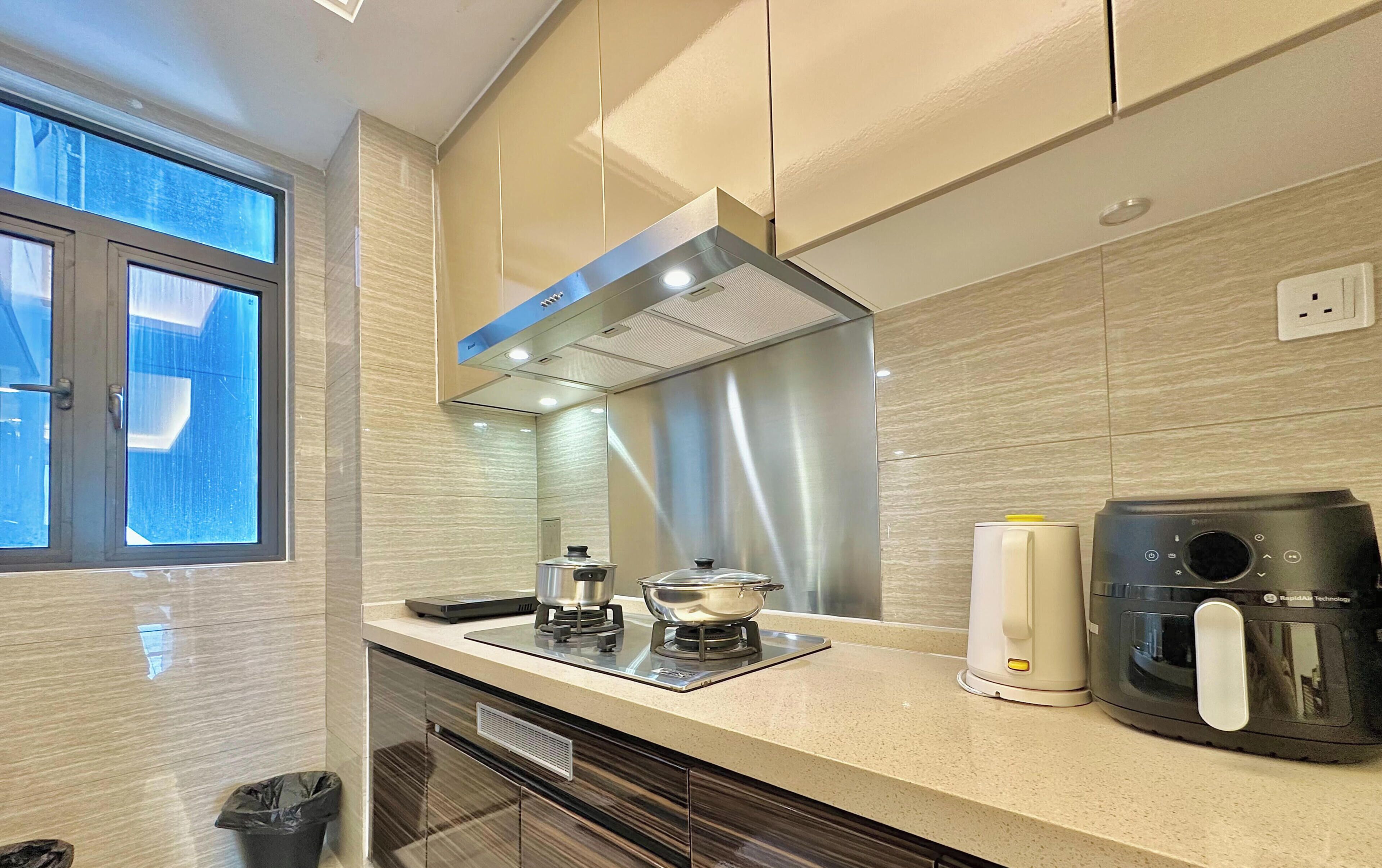 A modern kitchen with a stove, coffee maker, and a window.
