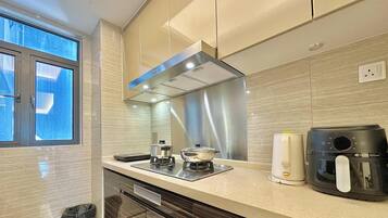 A modern kitchen with a stove, coffee maker, and a window.