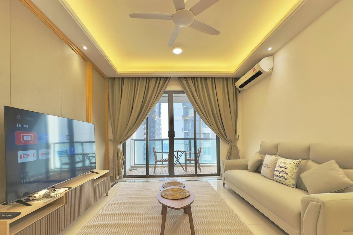 Un salon moderne doté d’un téléviseur à écran plat, d’un ventilateur de plafond et d’un balcon avec une table et des chaises.