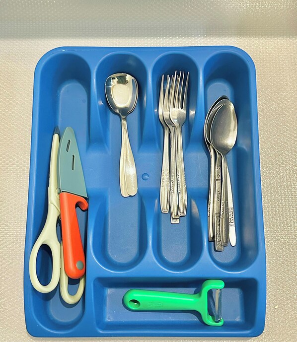 A blue tray with various kitchen utensils including a pair of scissors, a spoon, a fork, and a green-handled peeler. - R&F Princess Cove near CIQ by Stayrene (Johor Bahru)