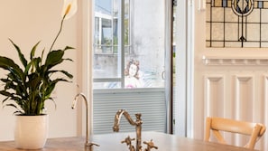 Ein Zimmer mit einem Blumentopf, einem Waschbecken mit Wasserhahn und einem Stuhl.