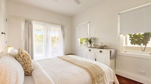 Un dormitorio con una cama grande, un aparador, un espejo y una ventana con vistas a la vegetación.