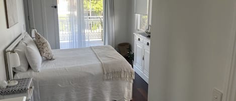 Un dormitorio con cama, mesita de noche y vista al exterior a través de una ventana.