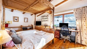 Een houten kamer met een bed, bureau en groot raam.