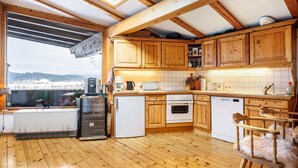 Een keuken met houten kasten, een koelkast, een oven, een vaatwasser en een raam met uitzicht op een besneeerd landschap.