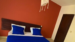 Una cama con ropa de cama azul y blanca, un cabecero de madera y un adorno colgante.