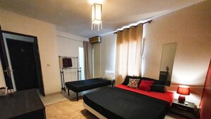A bedroom with a large bed, a bedside table, a lamp, a mirror, and a window with curtains. - Ylang Chambres d'Hôtes, Your Villa in Petite Terre, Mayotte (Dzaoudzi Labattoir)