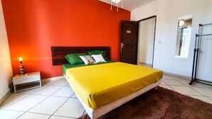 A bedroom with a bed, a nightstand, a lamp, a door, and a window. - Ylang Chambres d'Hôtes, Your Villa in Petite Terre, Mayotte (Dzaoudzi Labattoir)