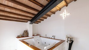 A modern bathroom with a freestanding bathtub, wooden beams on the ceiling, and a towel rack. - Giulia Suite with private hot tub (Rivalto Chianni)