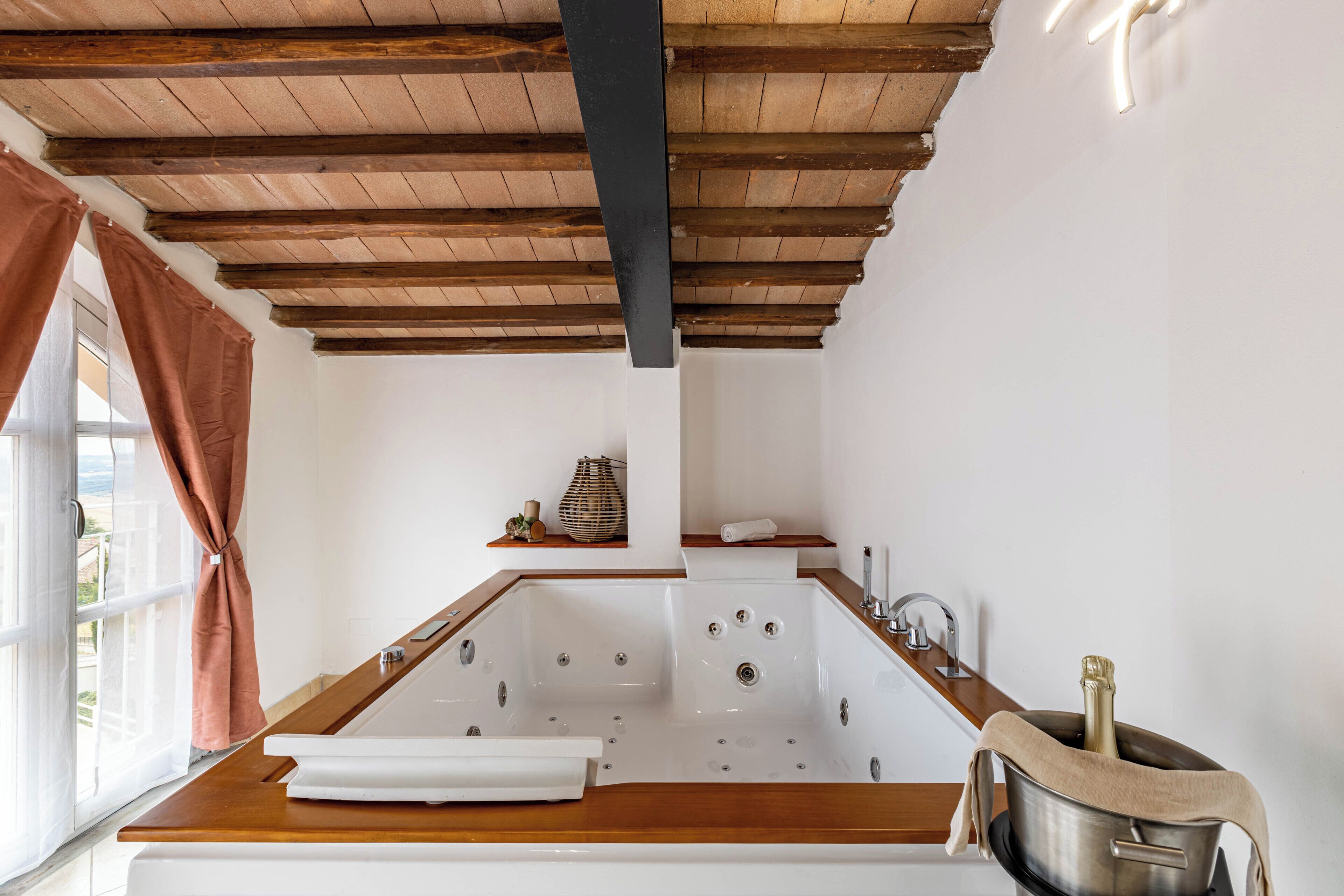 Une salle de bain avec une baignoire en bois, un lavabo et une fenêtre avec des rideaux.