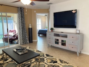 Een woonkamer met een flatscreen televisie, een bank, een salontafel en een eettafel.