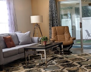 Un salon comprenant un canapé, une table basse, un lampadaire et un fauteuil.