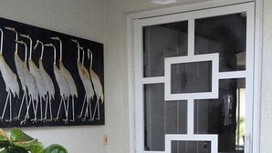 Eine Tür mit geometrischem Muster, ein Blumentopf und ein dekoratives Metallteil an der Wand.