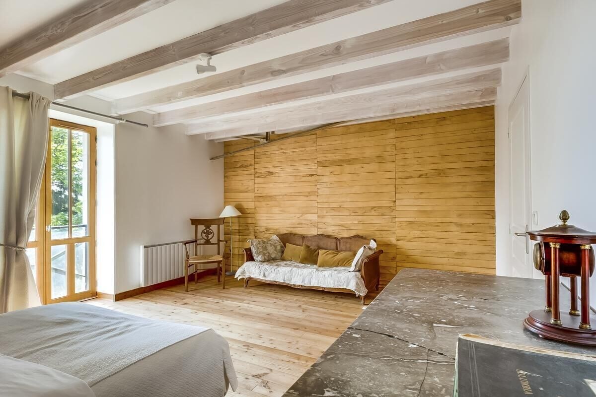 Een kamer met een houten plafond, een bank, een tafel en een radiator.