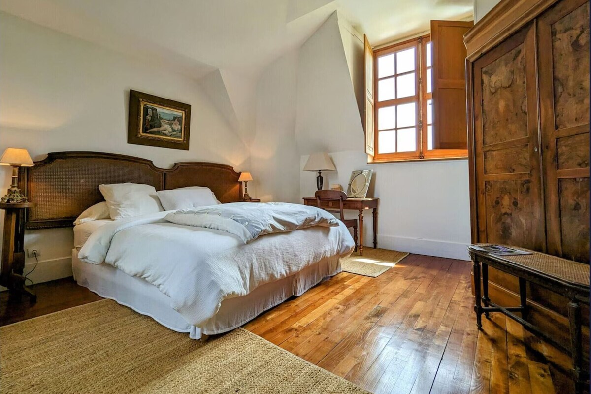 Een slaapkamer met een groot bed, een houten garderobe en een raam met gordijnen.