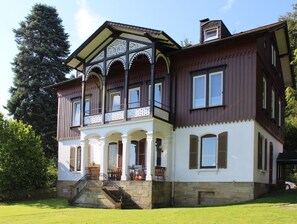 Een groot, twee verdiepingen tellend gebouw met een balkon en een overdekte veranda.