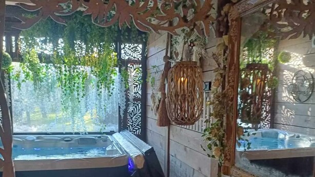 Una habitació acollidora amb una finestra gran, un tamboret de fusta, un sofà verd i un mirall decoratiu.