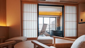 Um quarto japonês tradicional com tatames, uma mesa baixa e uma cadeira.