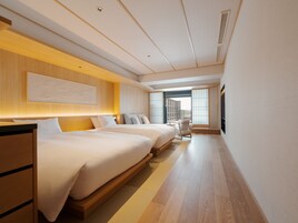 Habitación de hotel moderna con dos camas, un escritorio y vistas a la ciudad.