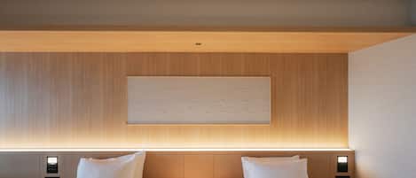 Ein Hotelzimmer mit zwei Betten, einem Holz-Kopfteil, einem Wandbild und Nachttischlampen.