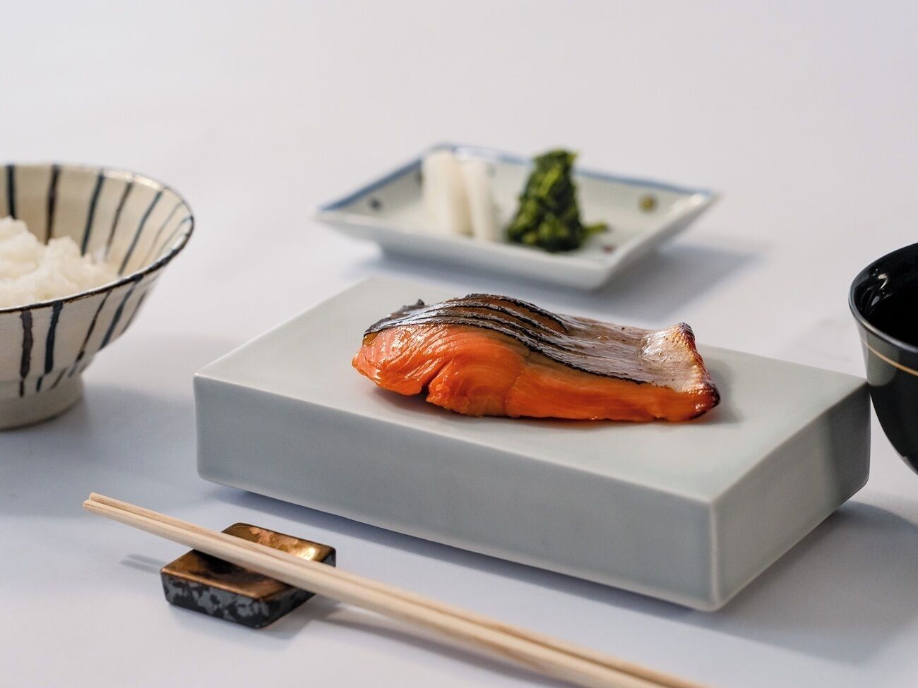 A sushi dish on a rectangular plate with chopsticks beside it.