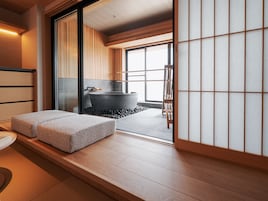 A traditional Japanese-style room with tatami flooring, a stone hot tub, and a sliding shoji screen.