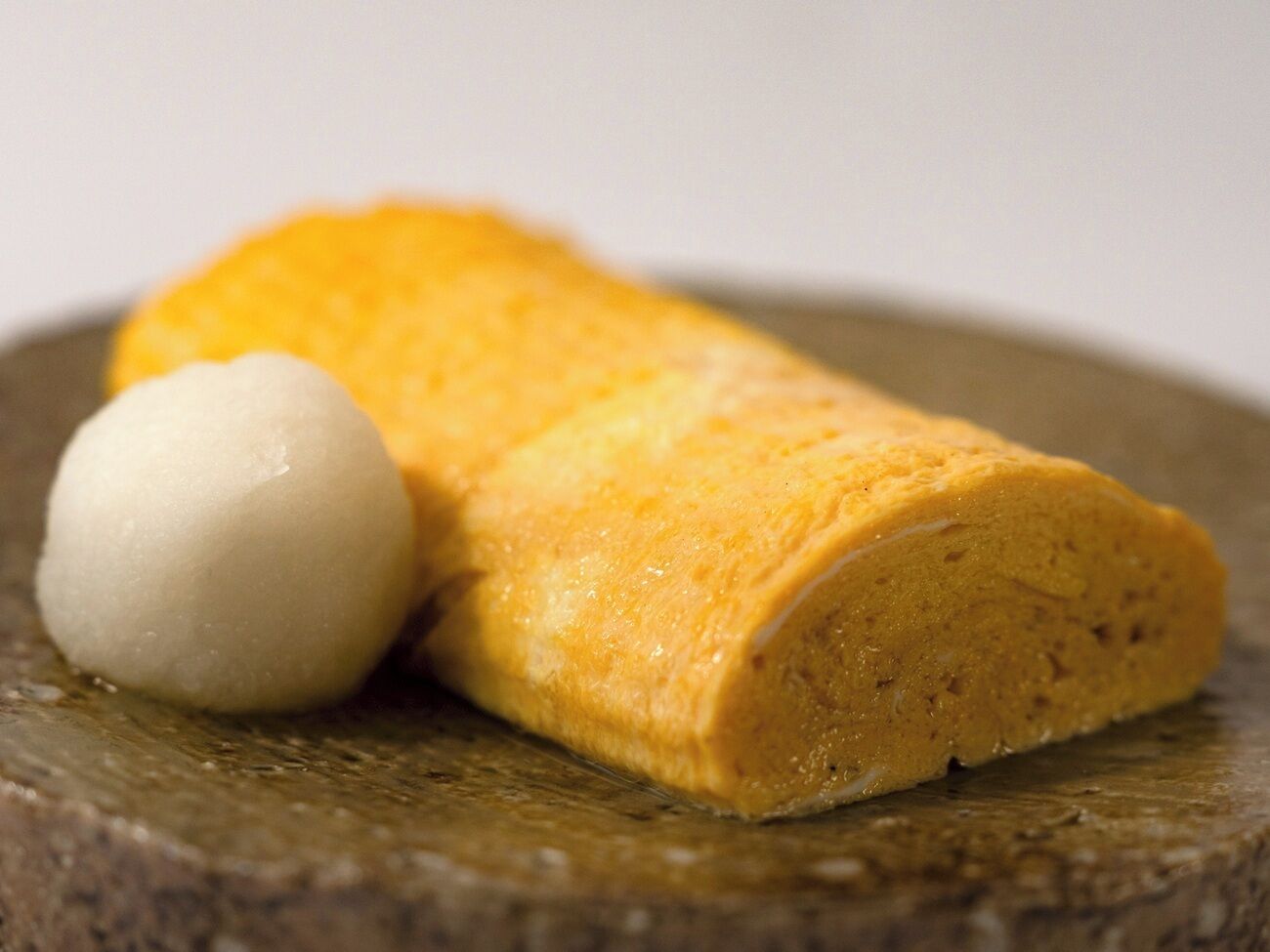 A rolled food item with a white spherical object beside it.
