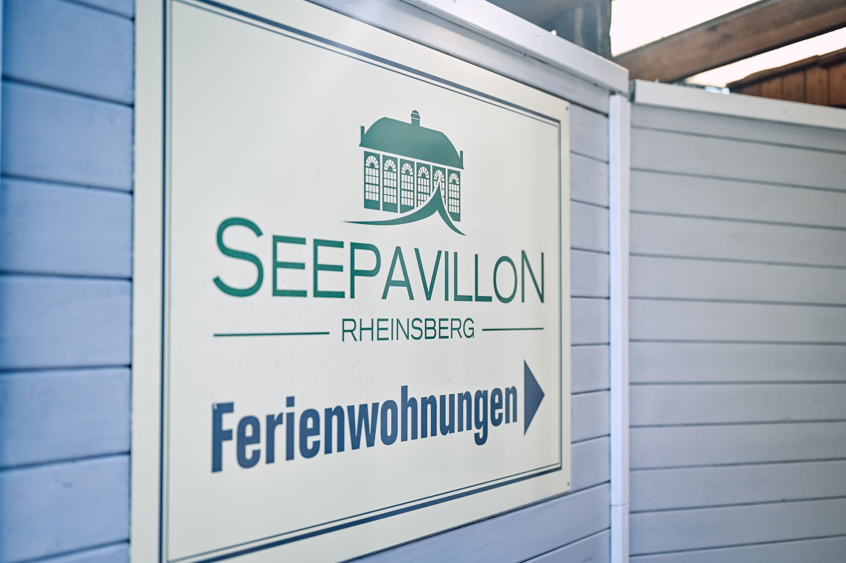 Un cartel para 'SEEPAVILLON' que indica 'Ferienwohnungen' (apartamentos vacacionales) en 'RHEINSBERG'.