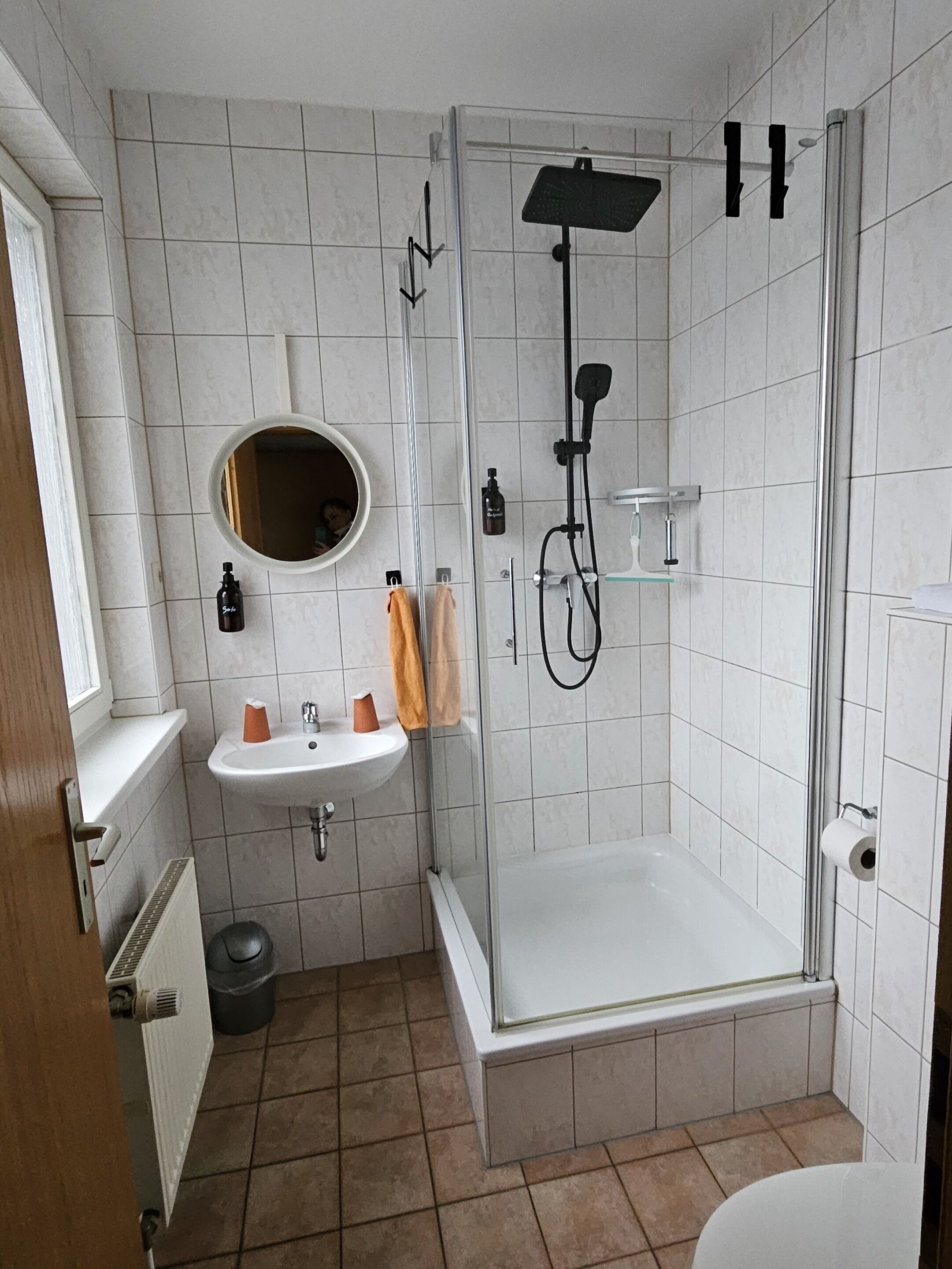 Ein Badezimmer mit einer Duschkabine, einem Waschbecken mit Spiegel und einer Toilette.