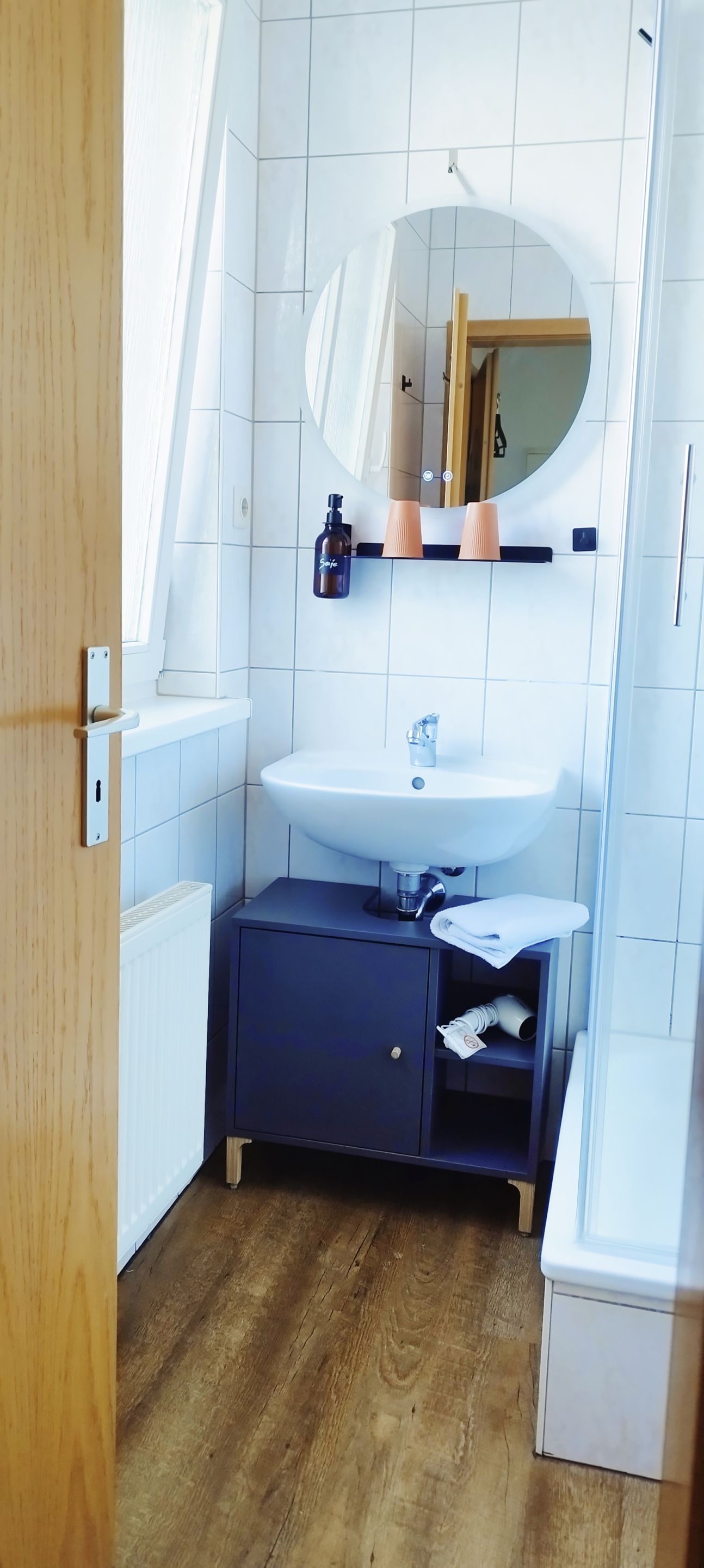 A bathroom with a white sink, a mirror, and a wooden cabinet.