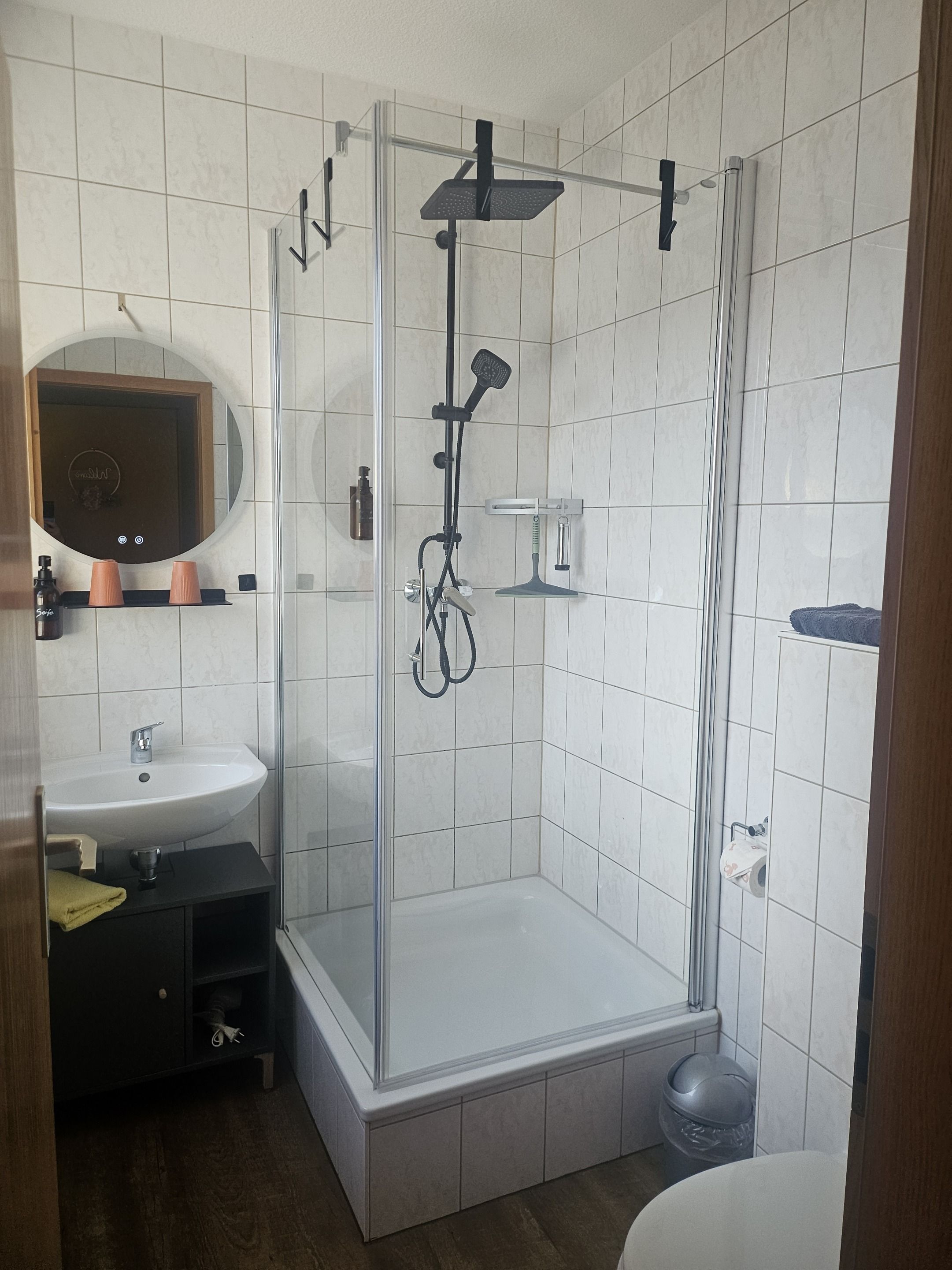 Un baño con ducha de vidrio, lavamanos y espejo.