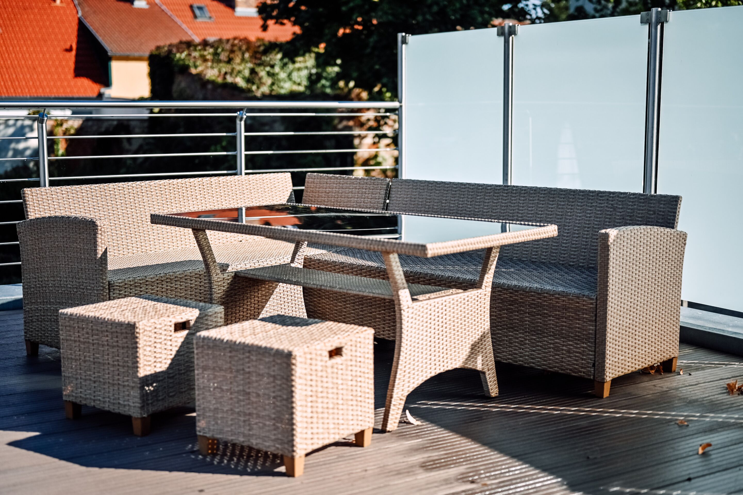 A wicker outdoor seating area with a table and chairs on a wooden deck.