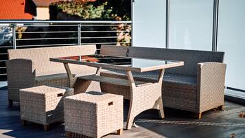 A wicker outdoor seating area with a table and chairs on a wooden deck.