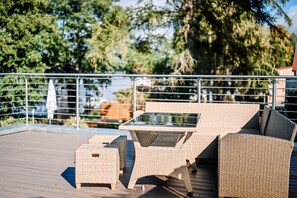 Una terrazza con mobili in vimini, tra cui un tavolo e due sedie.