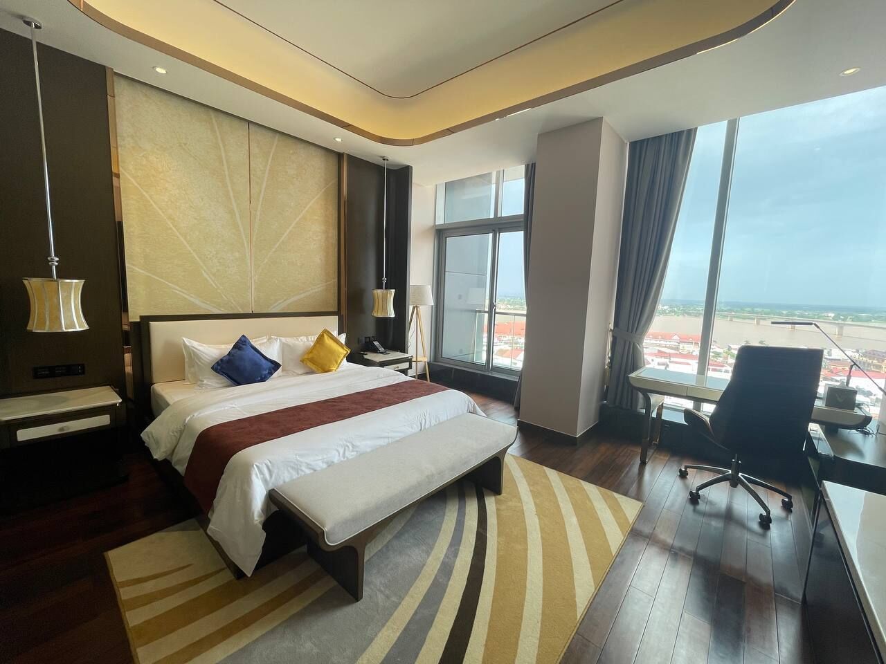 Ein modernes Hotelzimmer mit einem großen Bett, einem Schreibtisch und Blick auf eine Stadtansicht.