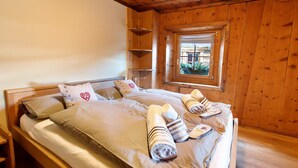 Ein holzgetäfeltes Zimmer im Chalet-Stil mit einem Bett, Kissen und Handtüchern.