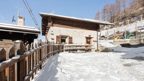 Ein Gebäude aus Holz mit einem geneigten Dach, einem Holzzaun und schneebedecktem Boden.