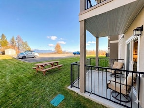 Ein Balkon mit Gartenmöbeln, einem Picknicktisch und Blick auf einen Parkplatz mit Autos.