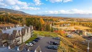 Ein Hotel mit Parkplatz, Blick auf den umliegenden Wald und Berge in der Ferne.