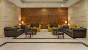 Een hal met twee banken en stoelen, een houten wand en inbouwspots.