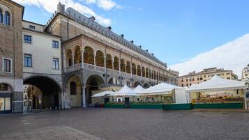Une cour intérieure abritant un bâtiment historique, caractérisé par des arcades et un espace couvert où se trouvent des étals de marché.