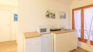 A compact kitchen with a microwave, a small refrigerator, a sink, and a wooden countertop. - GuestHost - Piazza della Frutta Studio Apartment 1 (Padua)