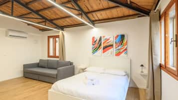 Una camera da letto con un letto, un divano grigio e arte astratta appesa al muro.