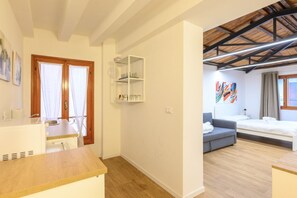 Una habitación compacta con kitchenette, un sofá, una cama y techo de madera.