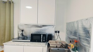 A compact kitchenette with a microwave, a sink, and a small countertop. - Cozy Studio in Hornchurch With Extra Bed (Hornchurch)
