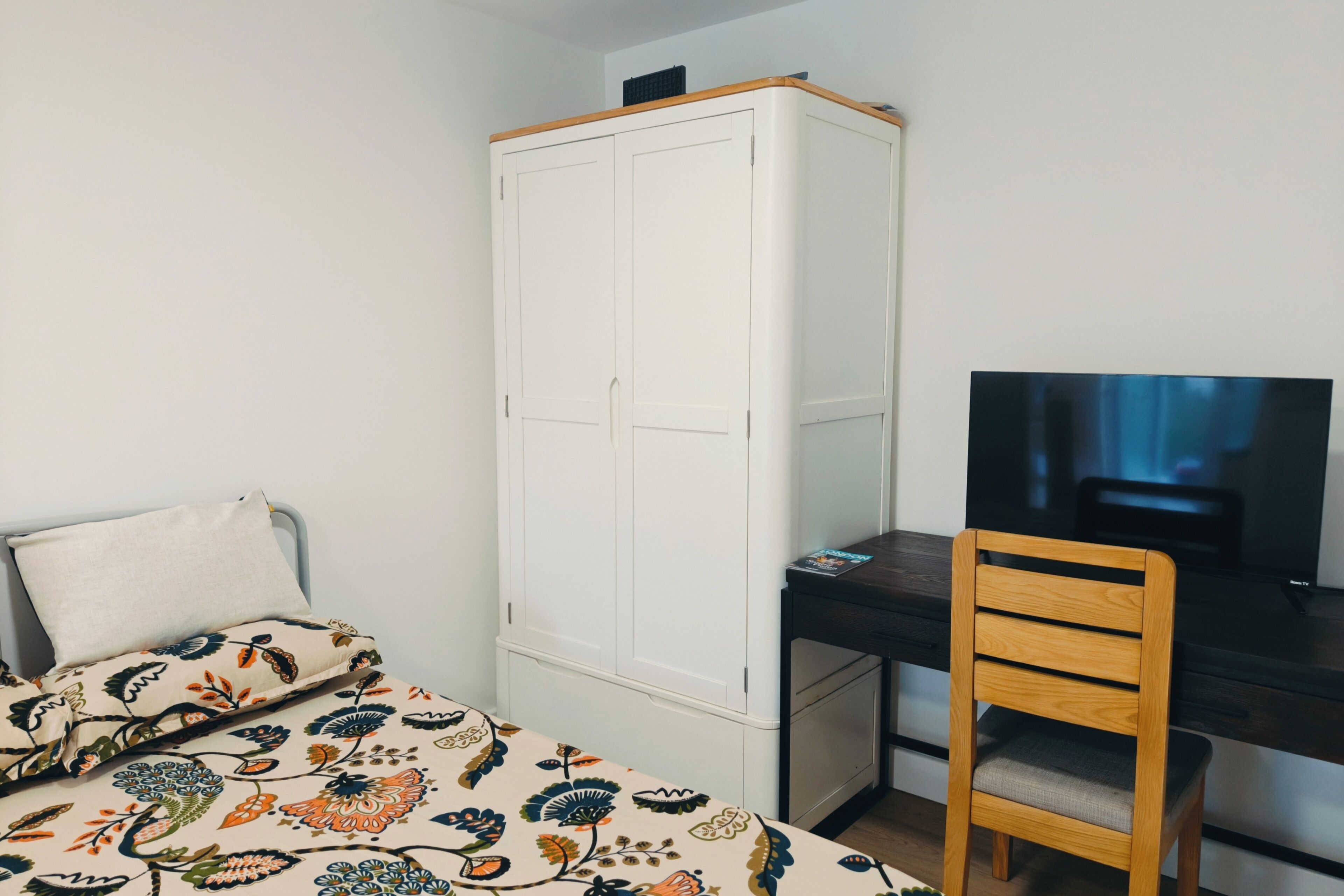 Ein Schlafzimmer mit einem Bett, einem Kleiderschrank, einem Schreibtisch mit Stuhl und einem Fernseher.