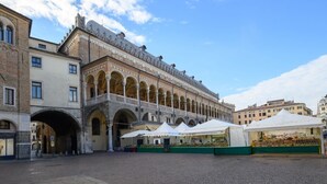 Un cortile con un edificio storico caratterizzato da archi e una zona coperta con bancarelle di mercato.